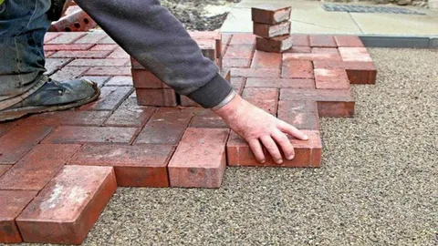 Professional installation of red brick interlocking pavers in a herringbone pattern on a sand base by Target Landscaping Inc.