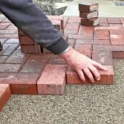 Professional installation of red brick interlocking pavers in a herringbone pattern on a sand base by Target Landscaping Inc.